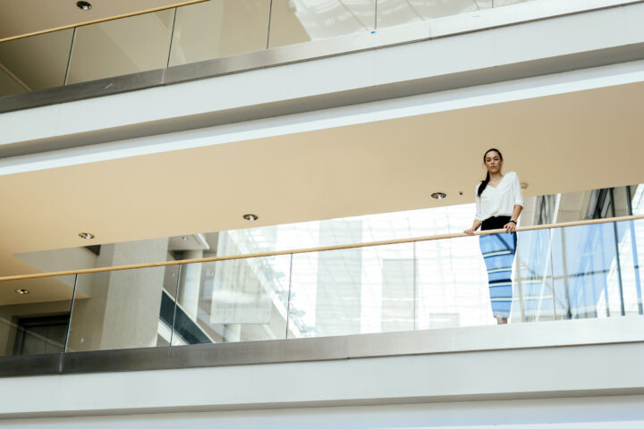 A woman looking over glass balustrades inside her home.